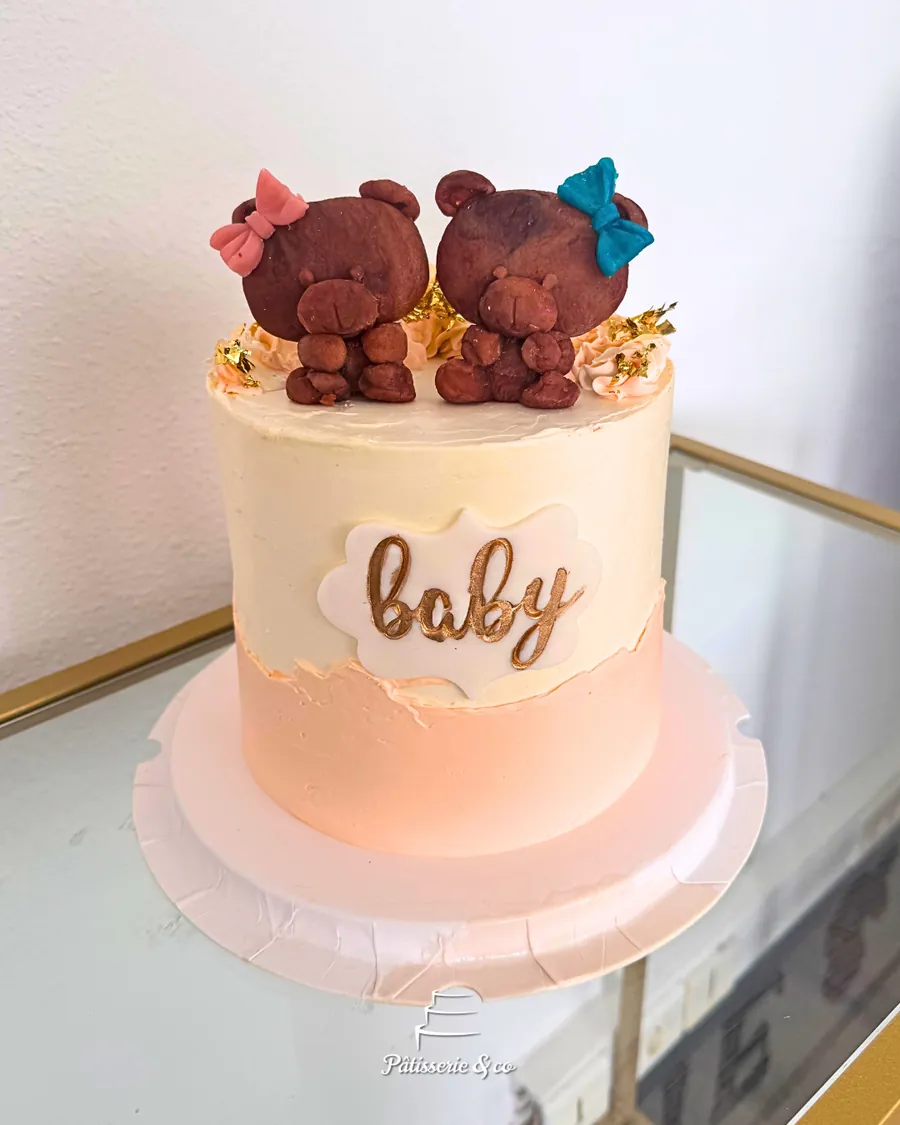 Gâteau rose et crème avec l'inscription baby en lettres dorées et deux oursons